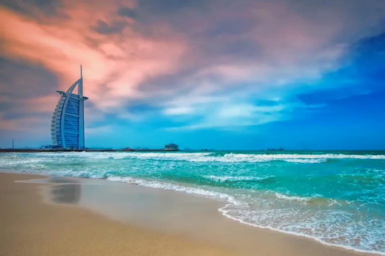 Tours 26 Burj Al Arab hotel and Jumeirah Beach in Dubai with turquoise sea and dramatic sunset sky