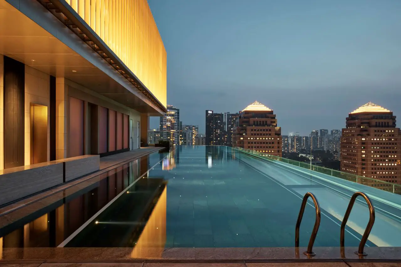 Rooftop infinity pool at COMO Metropolitan Singapore overlooking the Orchard Road skyline at dusk