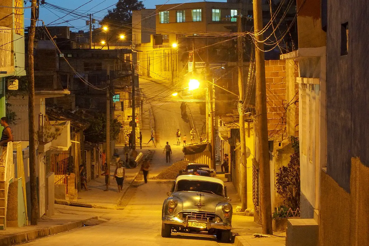 Night street scene in Havana, Cuba with vintage car and dim street lighting during power shortages