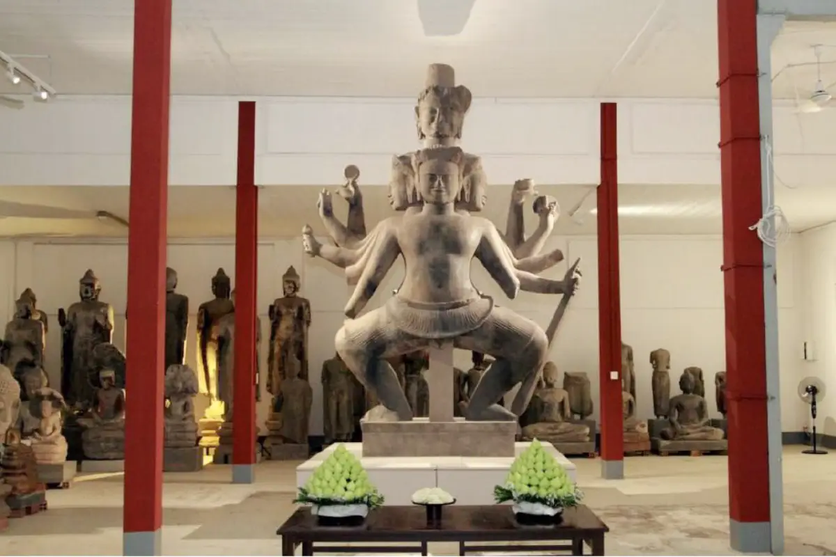 Restored Dancing Shiva statue displayed in a museum in Cambodia, featuring multiple arms and detailed ancient stone craftsmanship