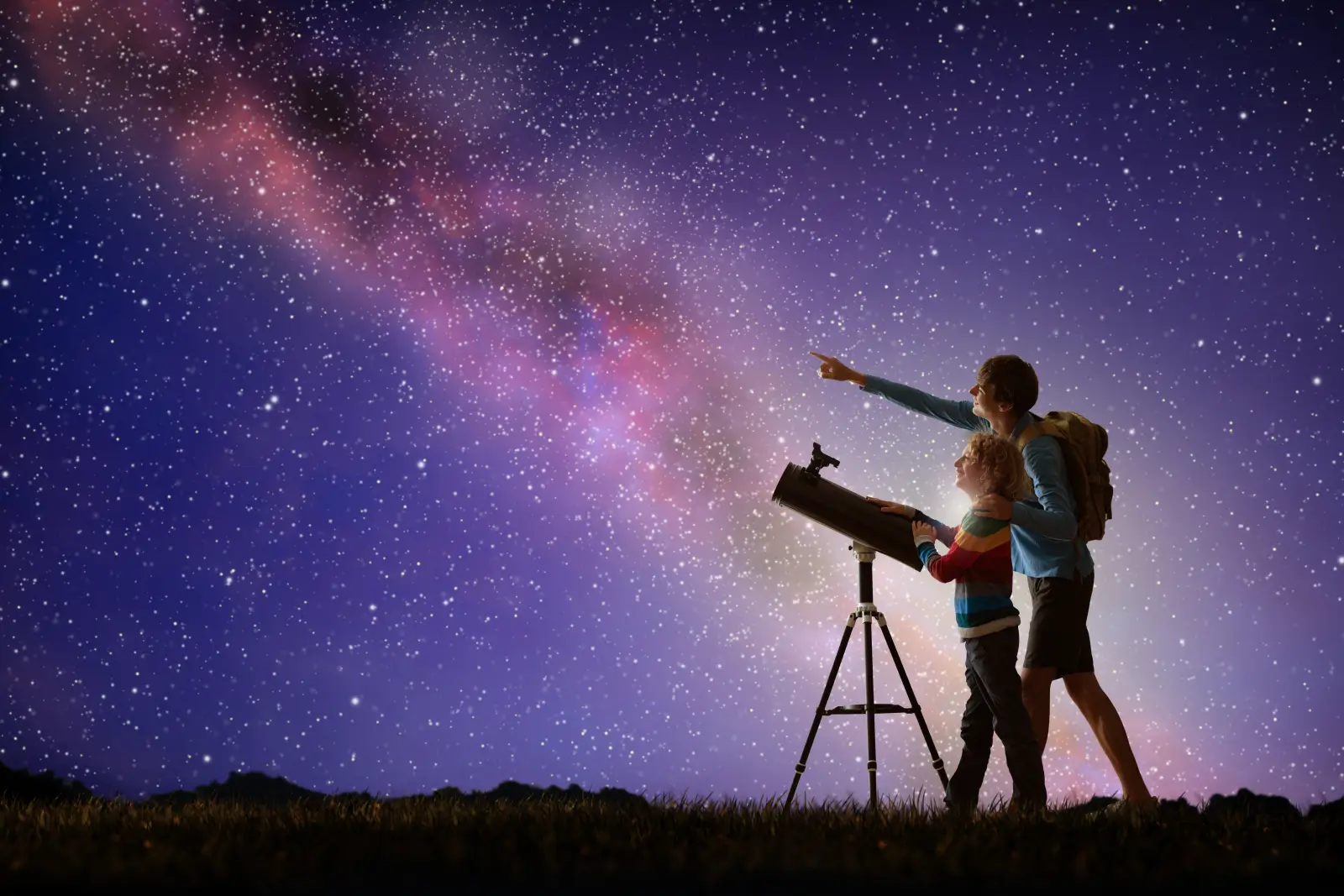 Family stargazing with a telescope under a star-filled night sky, pointing toward the Milky Way