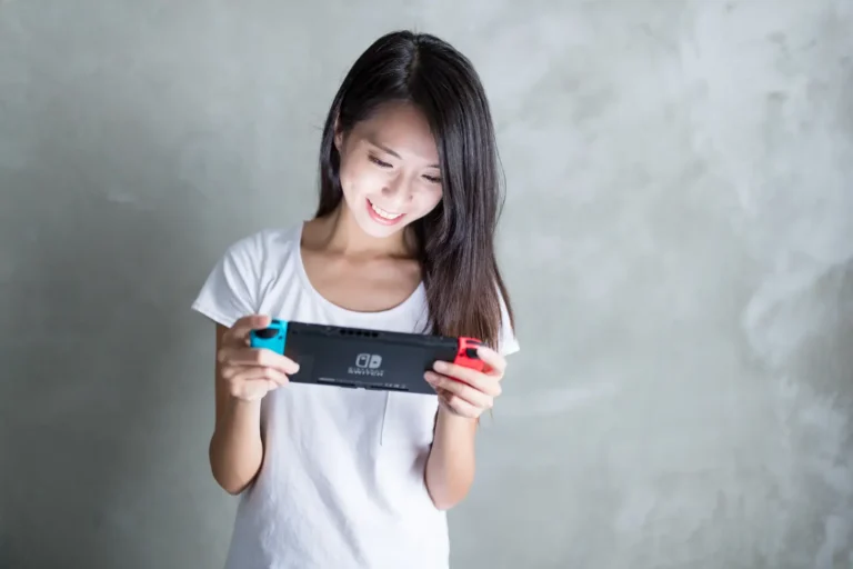 Other News 21 Woman playing Nintendo Switch handheld console at home, smiling while gaming, illustrating female gaming participation and platform preferences