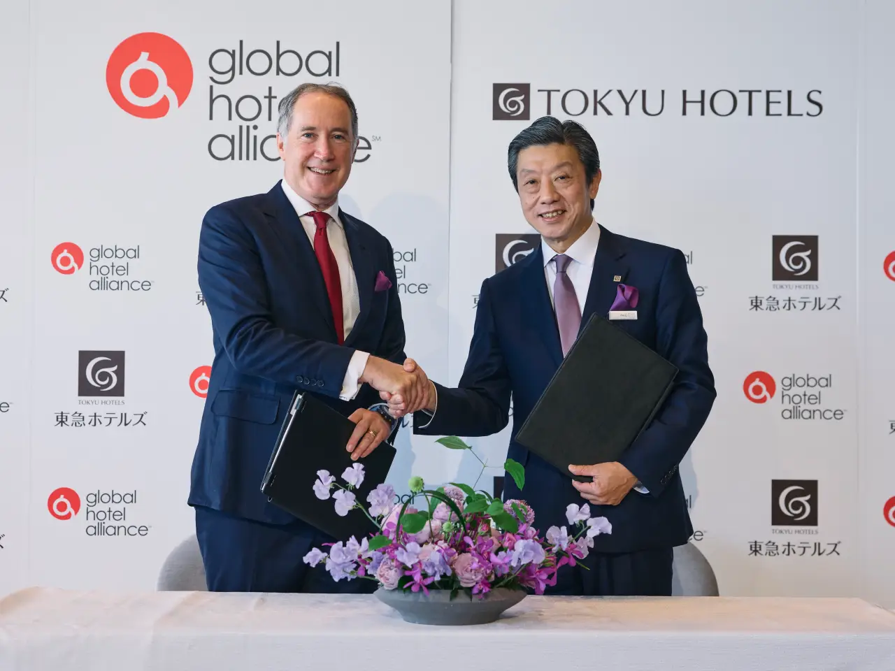 Chris Hartley of Global Hotel Alliance and Takashi Takei of Tokyu Hotels shake hands after signing partnership agreement in Tokyo