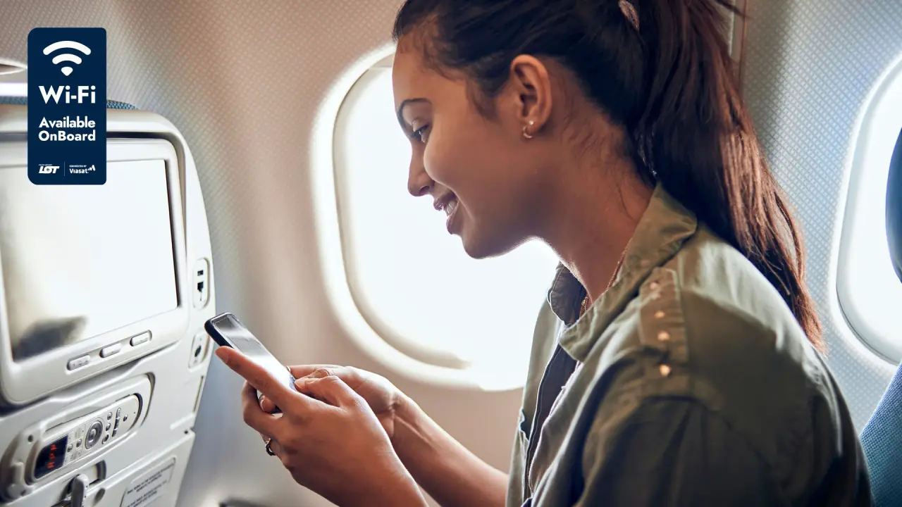 Airline passenger using smartphone with onboard Wi-Fi inside a LOT Polish Airlines aircraft cabin during a flight.