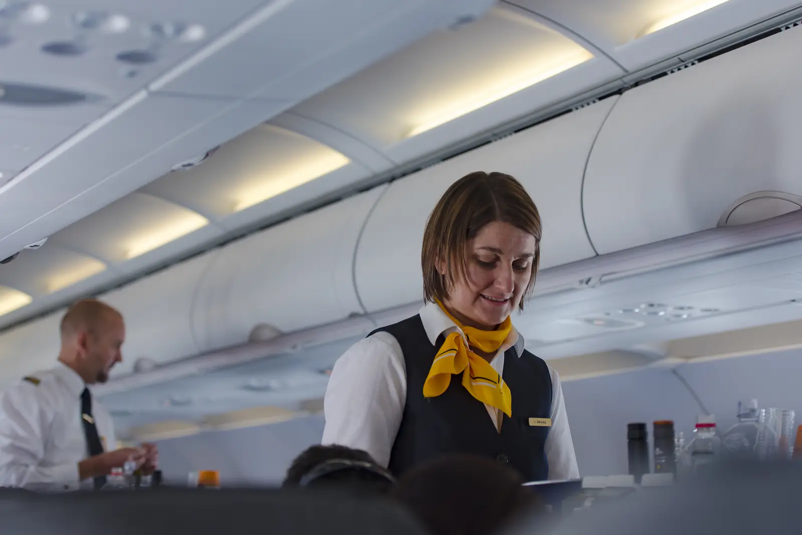 Flight attendant serving passengers in economy cabin during short-haul Lufthansa flight