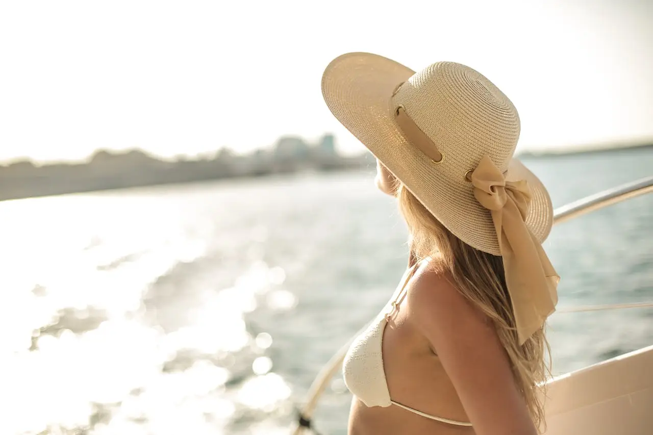 Woman wearing sun hat relaxing on a luxury yacht at sea during sunset