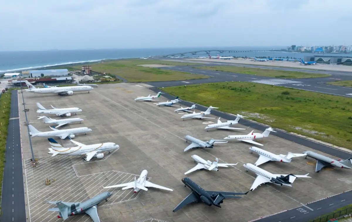 Aerial view of multiple private jets parked on an airport apron near the coastline in the Maldives