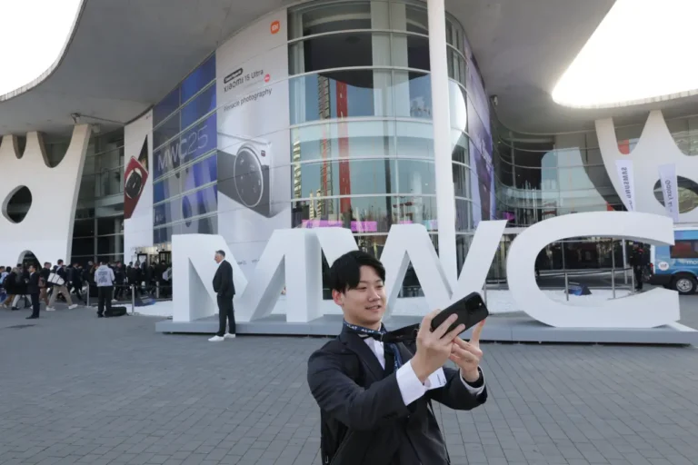 Attendee taking a selfie in front of the MWC sign outside Fira Barcelona during Mobile World Congress