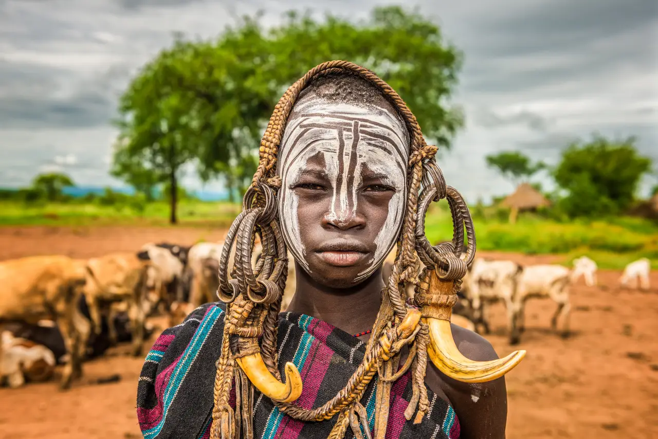 Mursi tribe boy with traditional lip ornaments and face paint in Ethiopia