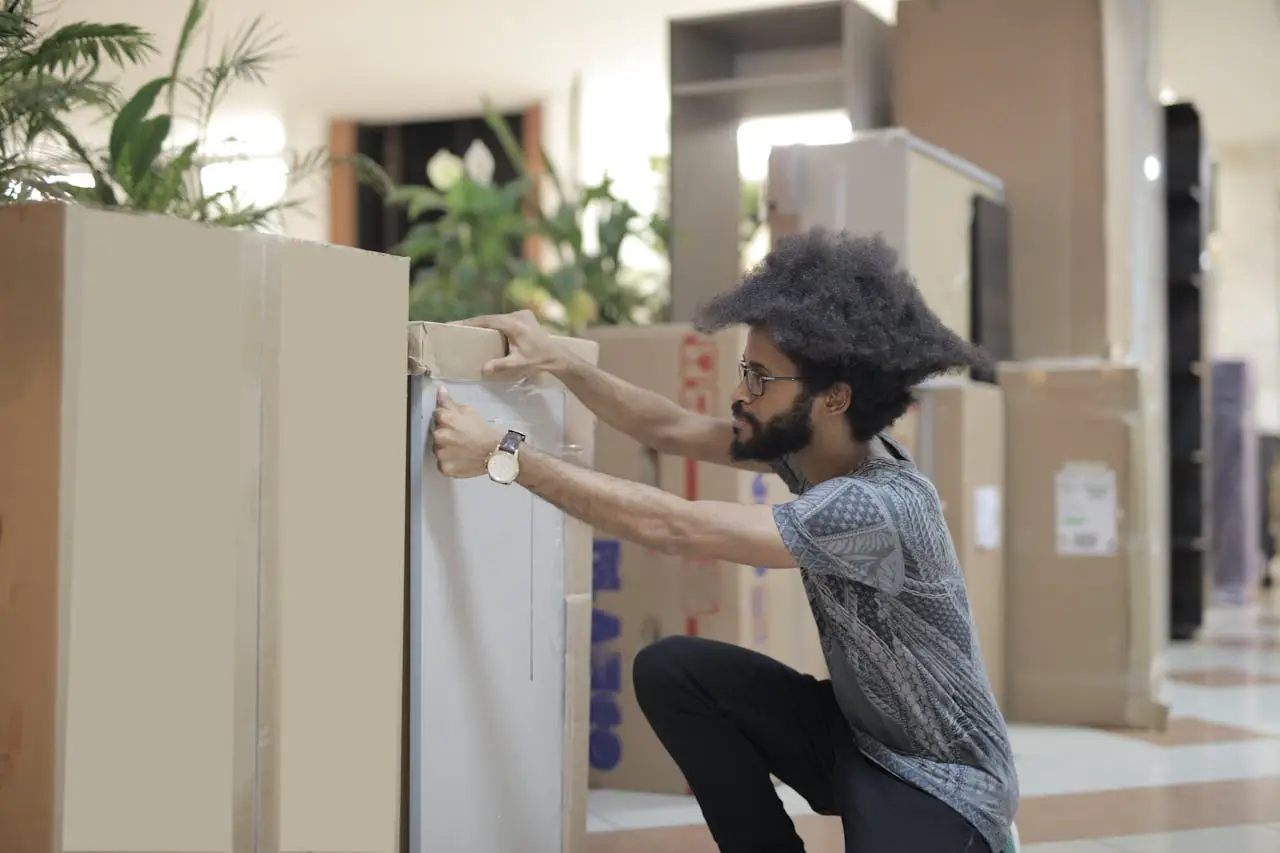 Man packing household items into cardboard boxes while preparing for a home move