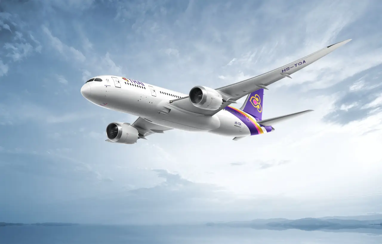Thai Airways widebody aircraft flying above clouds with purple and gold tail livery
