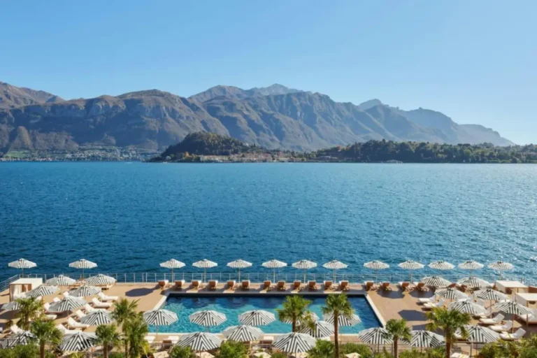 Tours 9 Floating pool and striped sun loungers at The Lake Como EDITION overlooking Lake Como and the surrounding mountains in Italy.