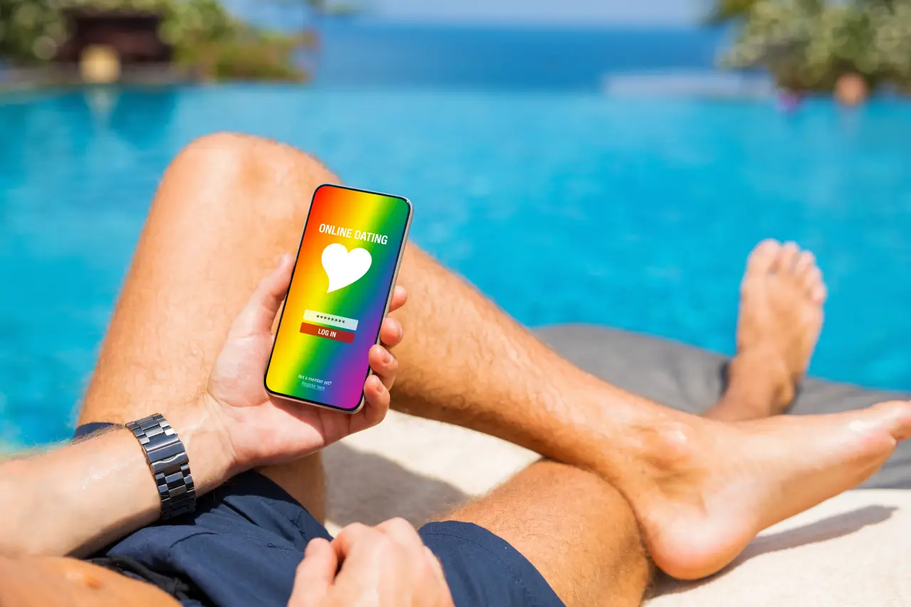 Do Dating Apps Actually Work When You'Re Traveling? 3 Traveler relaxing by a pool using an online dating app on a smartphone during a holiday