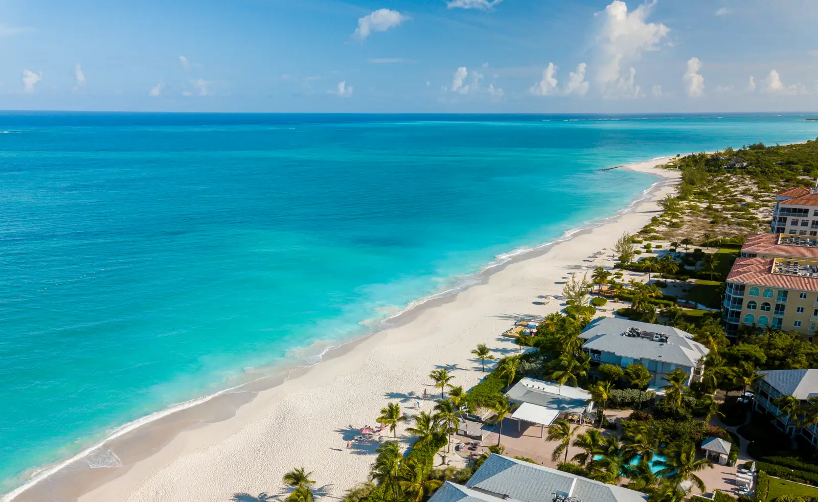 Aerial view of Turks and Caicos beach with turquoise water, white sand coastline, and luxury resorts along Grace Bay