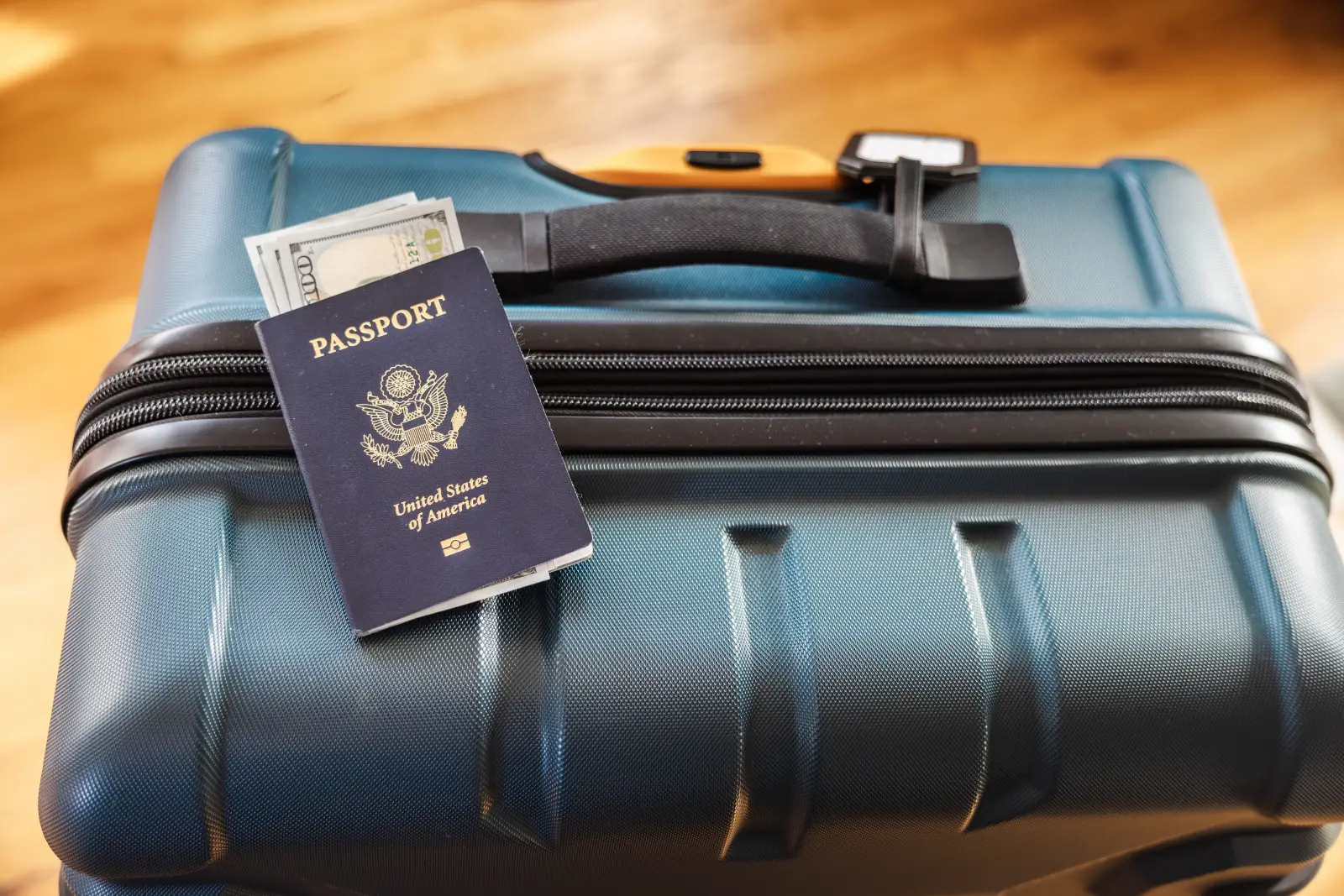 US passport with cash placed on a hard-shell suitcase ready for travel