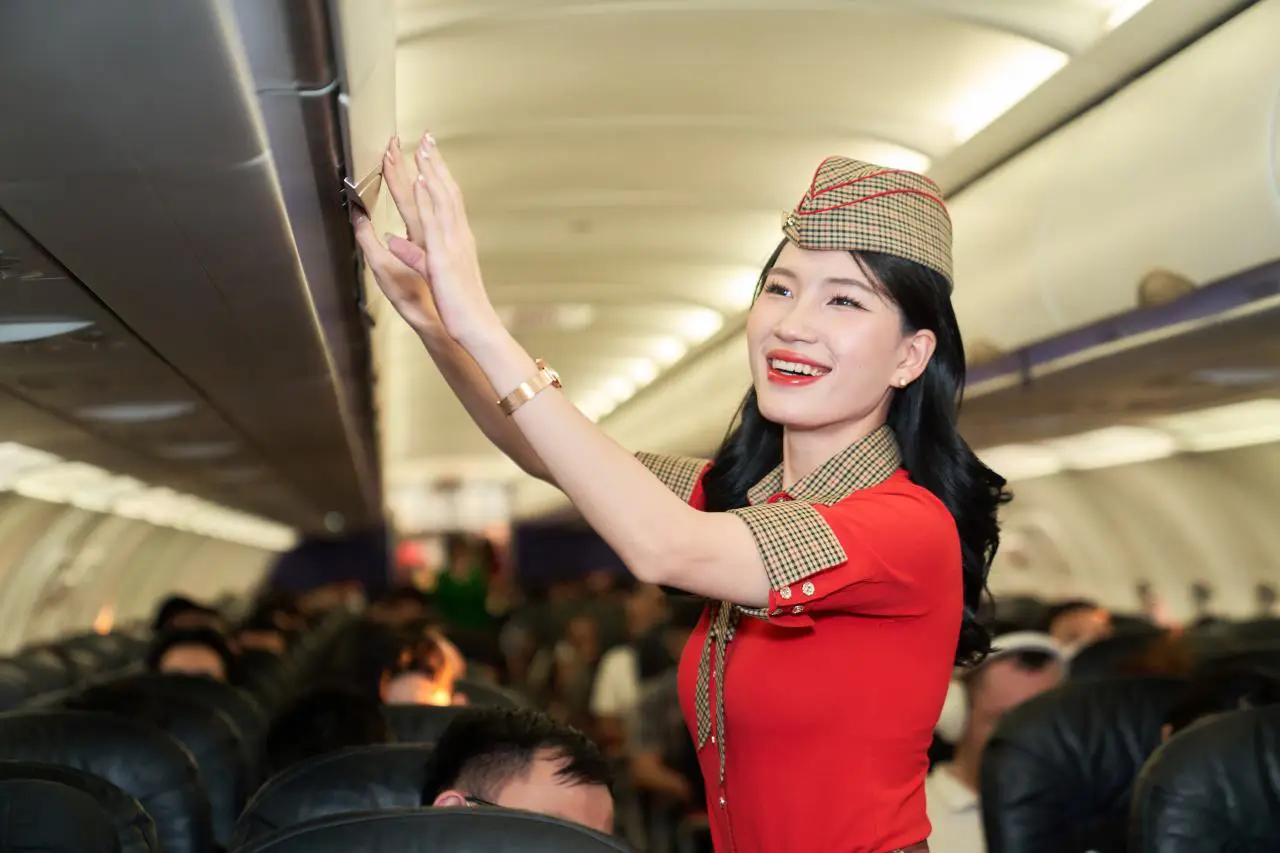 Vietjet cabin crew member assisting passengers inside aircraft cabin during flight