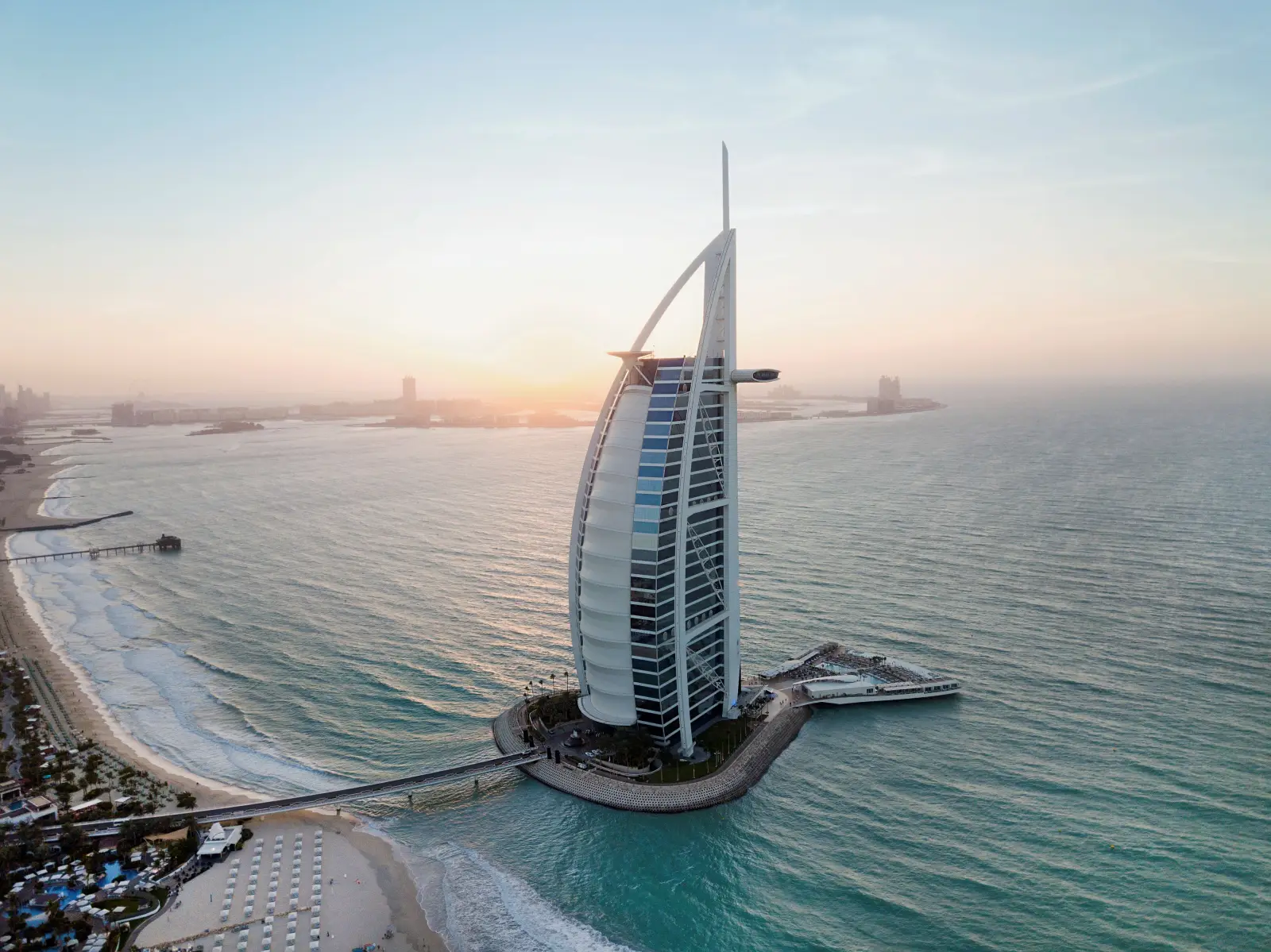 Aerial view of Burj Al Arab hotel in Dubai at sunset, iconic sail-shaped luxury hotel on its own island