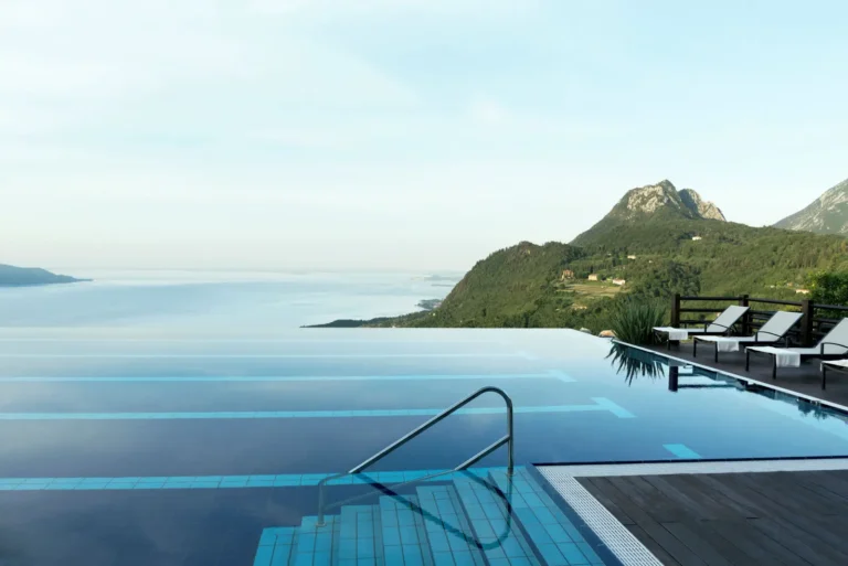 Infinity pool overlooking Lake Garda with mountain landscape and sun loungers at a luxury wellness resort