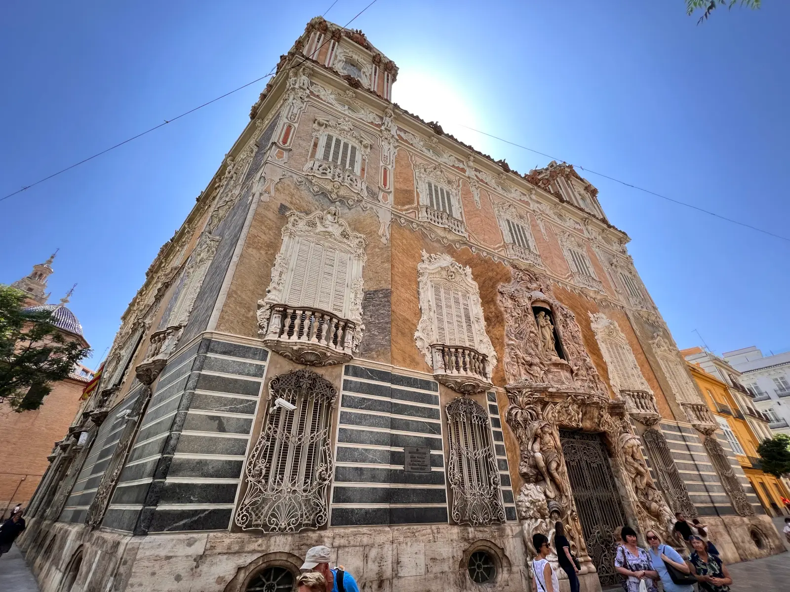 Ornate baroque facade of Palacio del Marqués de Dos Aguas in Valencia with detailed carvings and visitors below