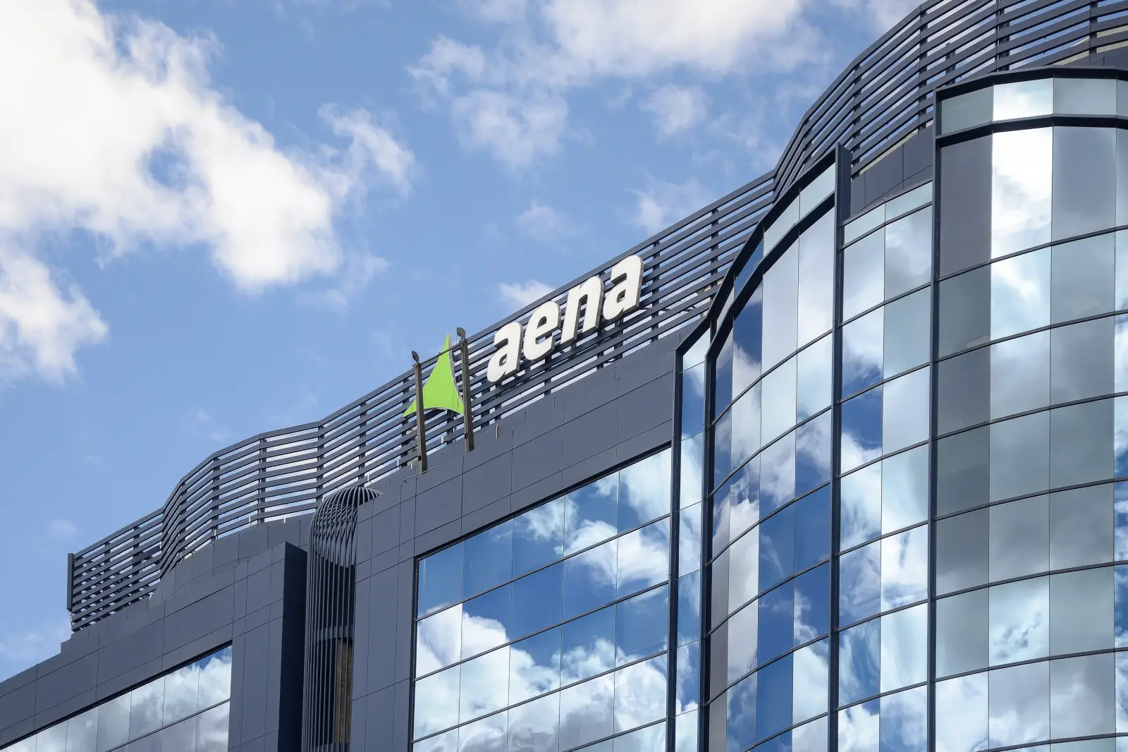 Aena headquarters building with logo on modern glass facade under blue sky
