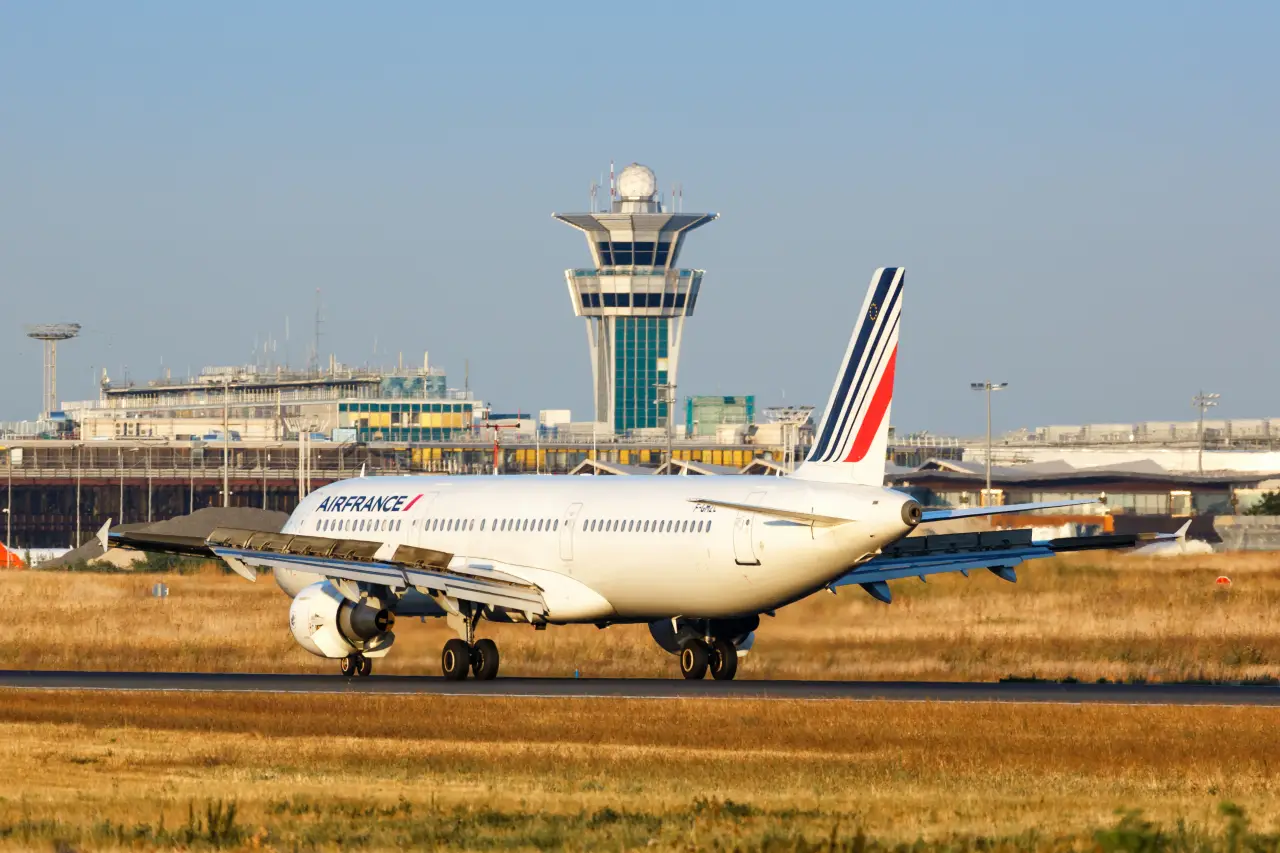 An Air France Airbus aircraft landing on the runway at Paris Orly Airport with the air traffic control tower in the background