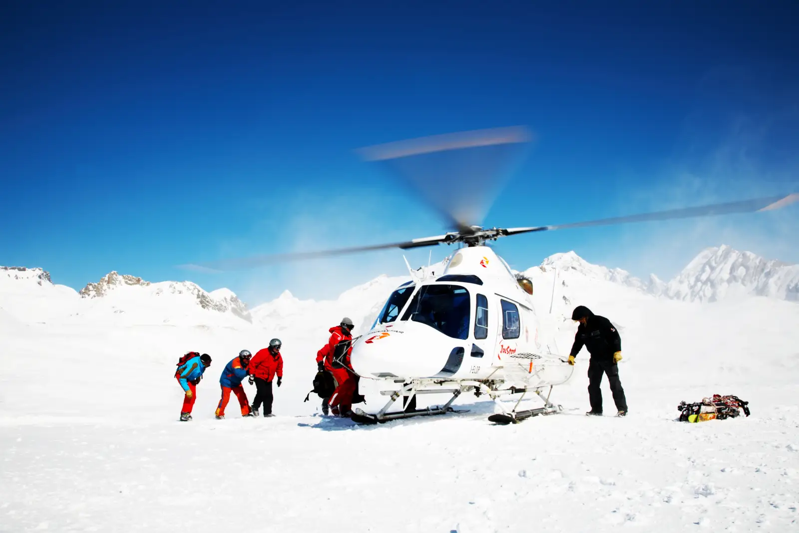 Rescue helicopter evacuating climbers on snowy Mount Everest with guides assisting passengers in high-altitude conditions