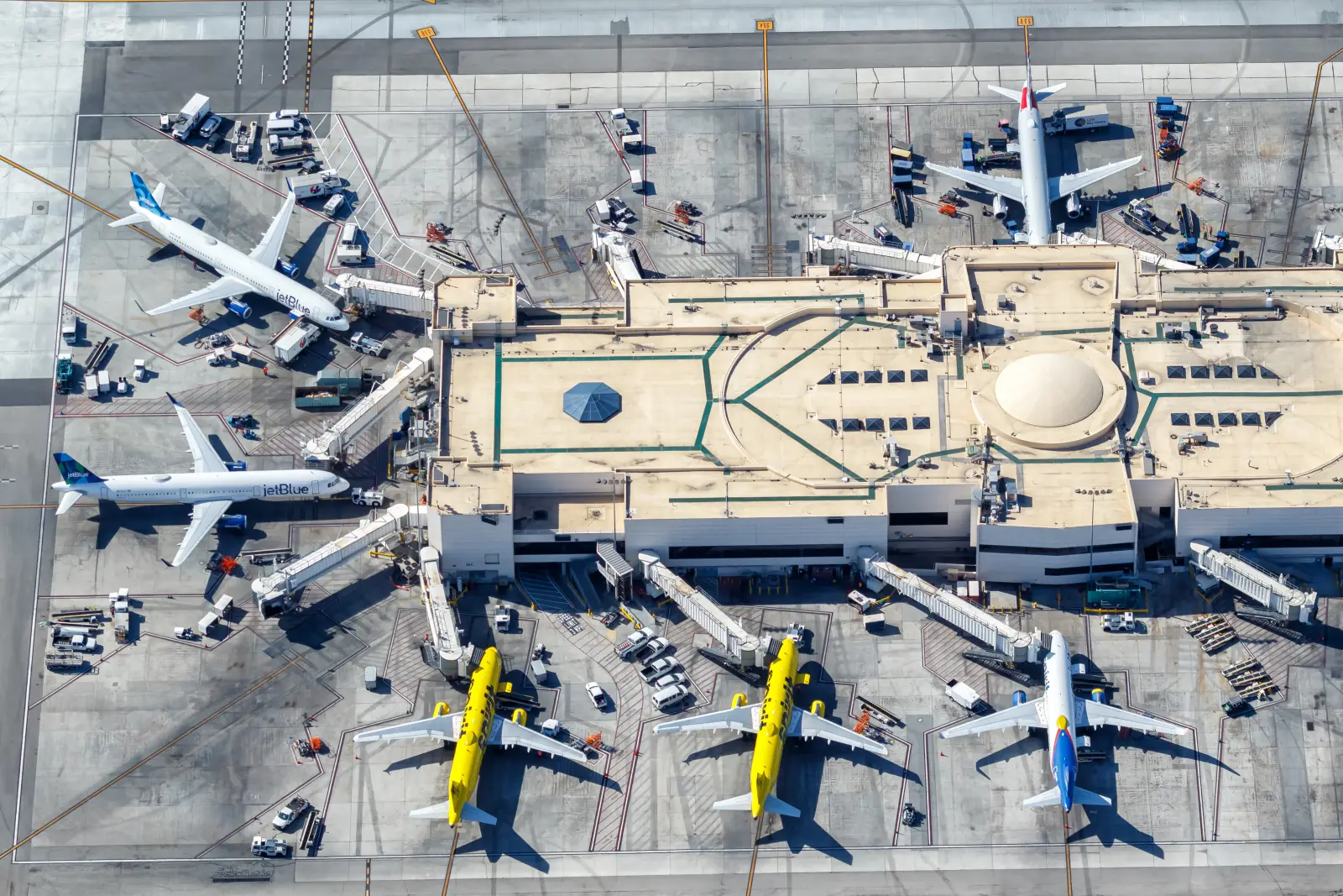 Aerial view of JetBlue and Spirit Airlines airplanes parked at gates at Los Angeles International Airport with ground operations visible