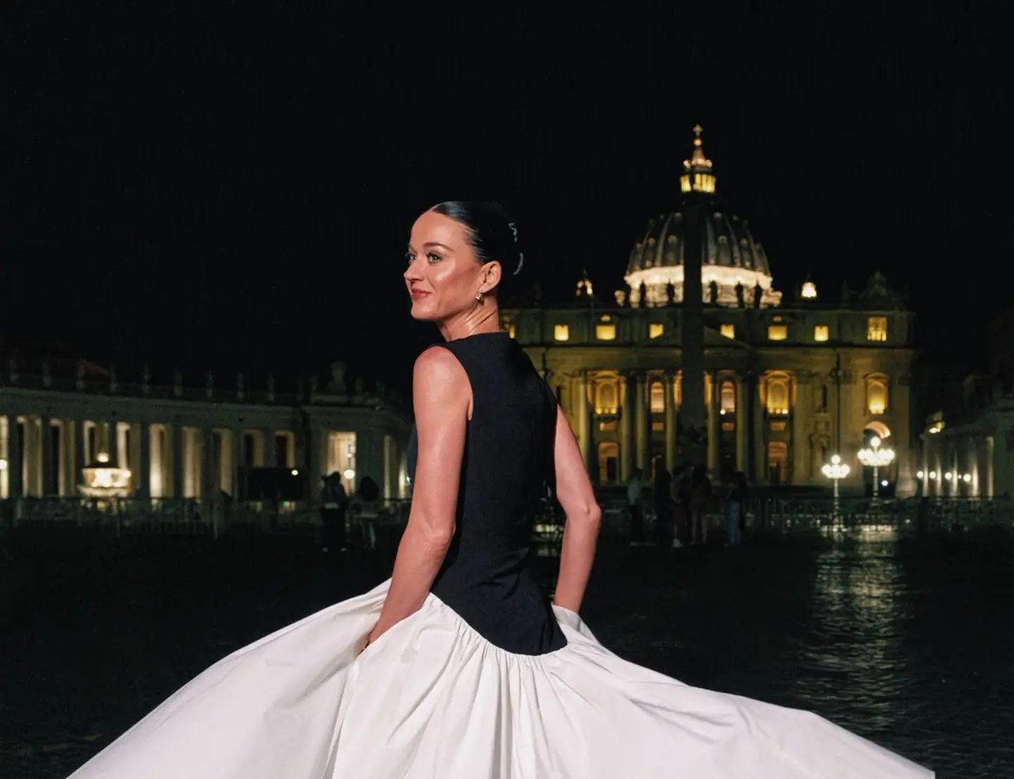 Katy Perry in elegant dress posing at night in St Peter’s Square with illuminated Vatican dome in Rome