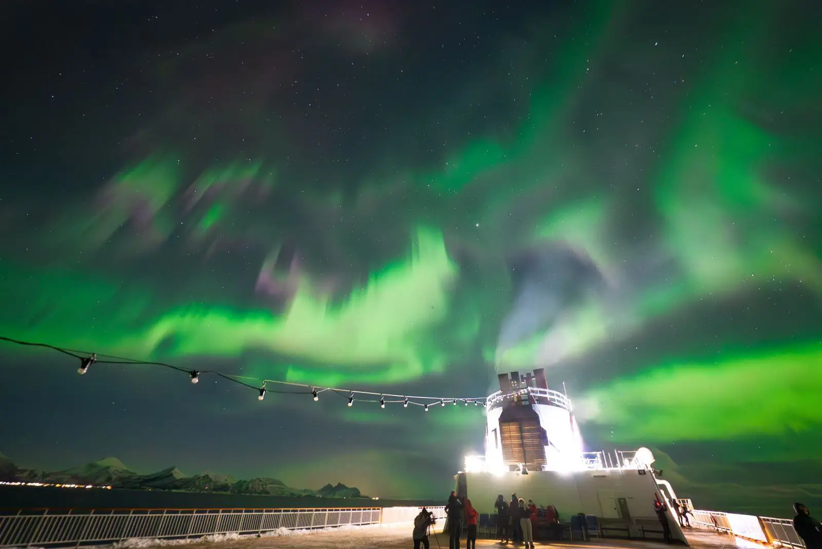 Rarely Witnessed ‘Pulsating’ Northern Lights Display Captured In Arctic Norway 3 Green and purple Northern Lights dance above the deck of a Hurtigruten ship sailing through Arctic Norway at night.