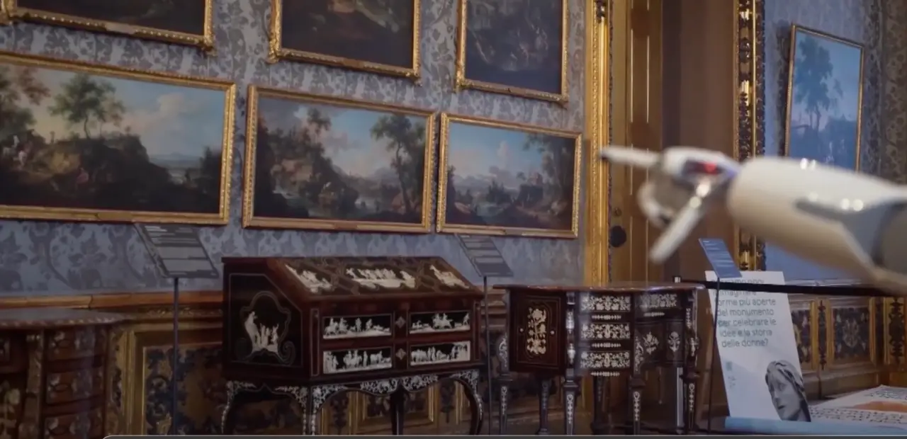The arm of the R1 humanoid robot visible in an ornate gallery room at Palazzo Madama in Turin, Italy, during a visitor guiding trial