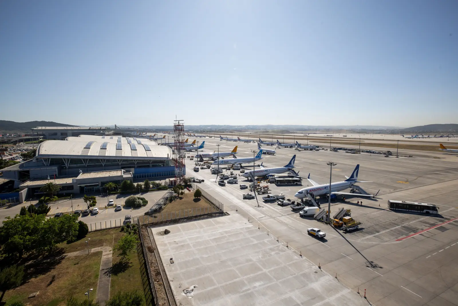 Aerial view of Istanbul Sabiha Gökçen Airport apron with multiple aircraft parked at the terminal on a clear sunny day