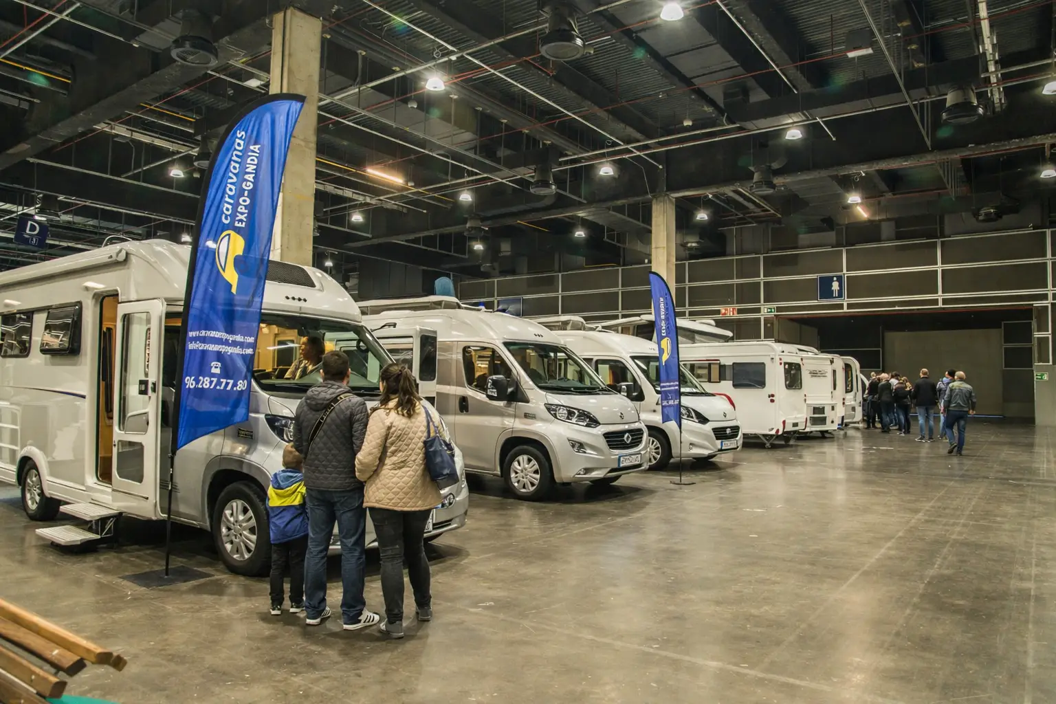 Visitors explore motorhomes and caravans inside a busy indoor exhibition hall at a Spain caravan fair