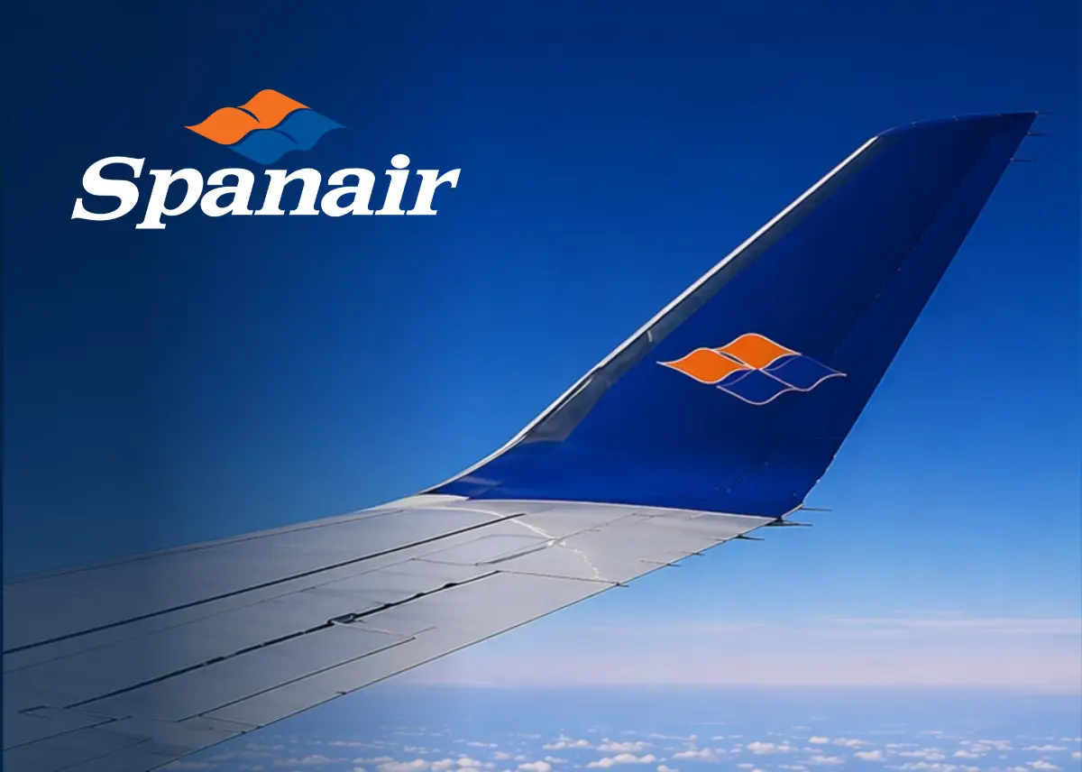 Spanair logo above aircraft wing in flight against blue sky