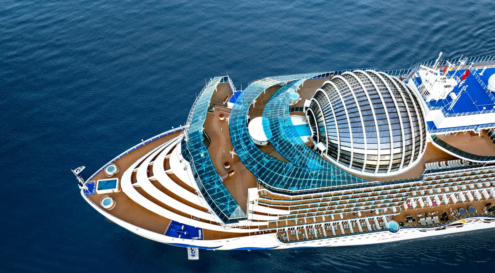 Aerial view of the Sun Princess cruise ship at sea, showcasing its modern glass dome and expansive deck areas