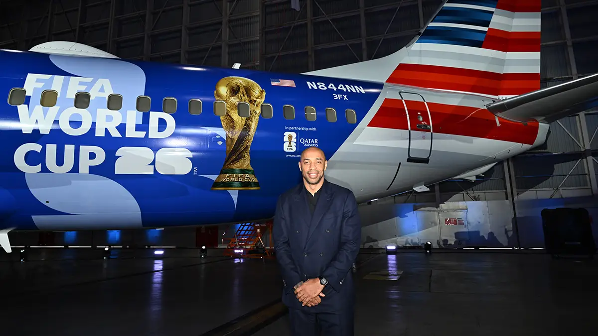 Thierry Henry poses in front of American Airlines Boeing 737-800 featuring FIFA World Cup 26 livery inside an aircraft hangar