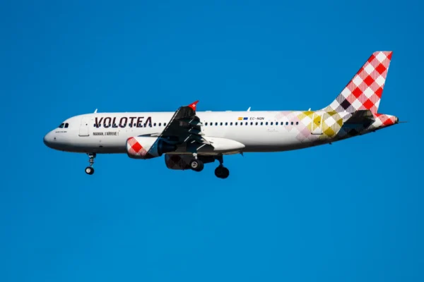Volotea Airbus A320 aircraft in flight against clear blue sky with landing gear deployed