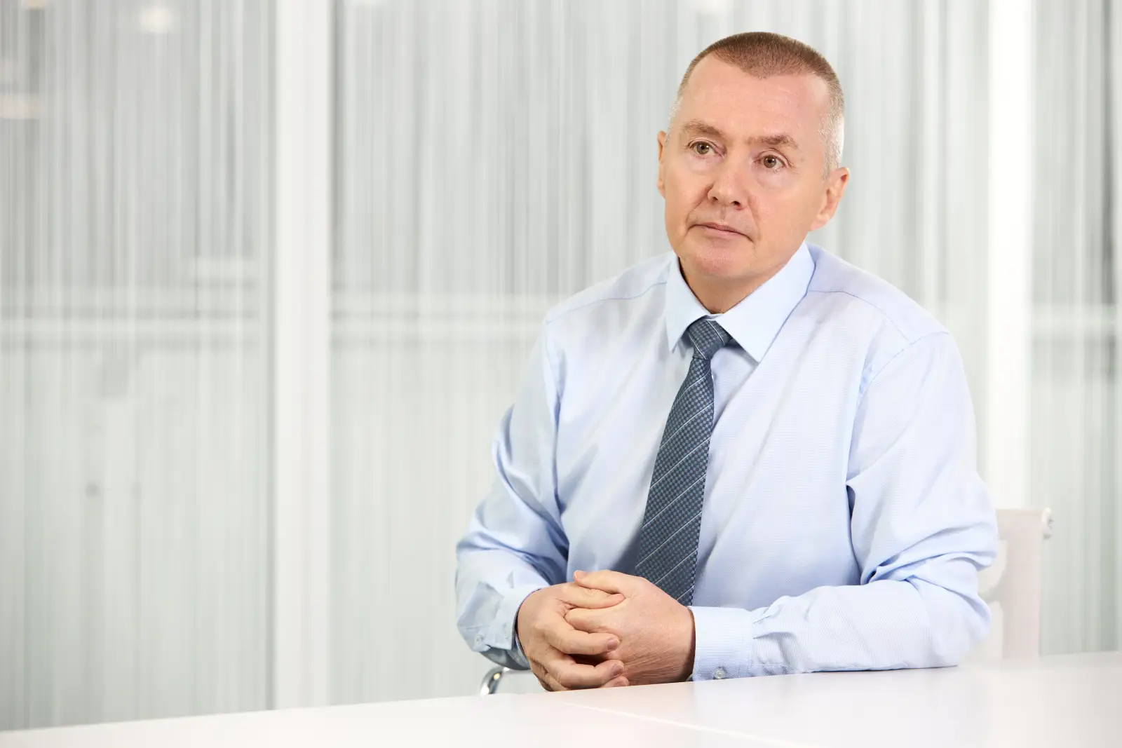 Willie Walsh, Senior airline executive in light blue shirt and tie seated at desk in office setting, professional portrait