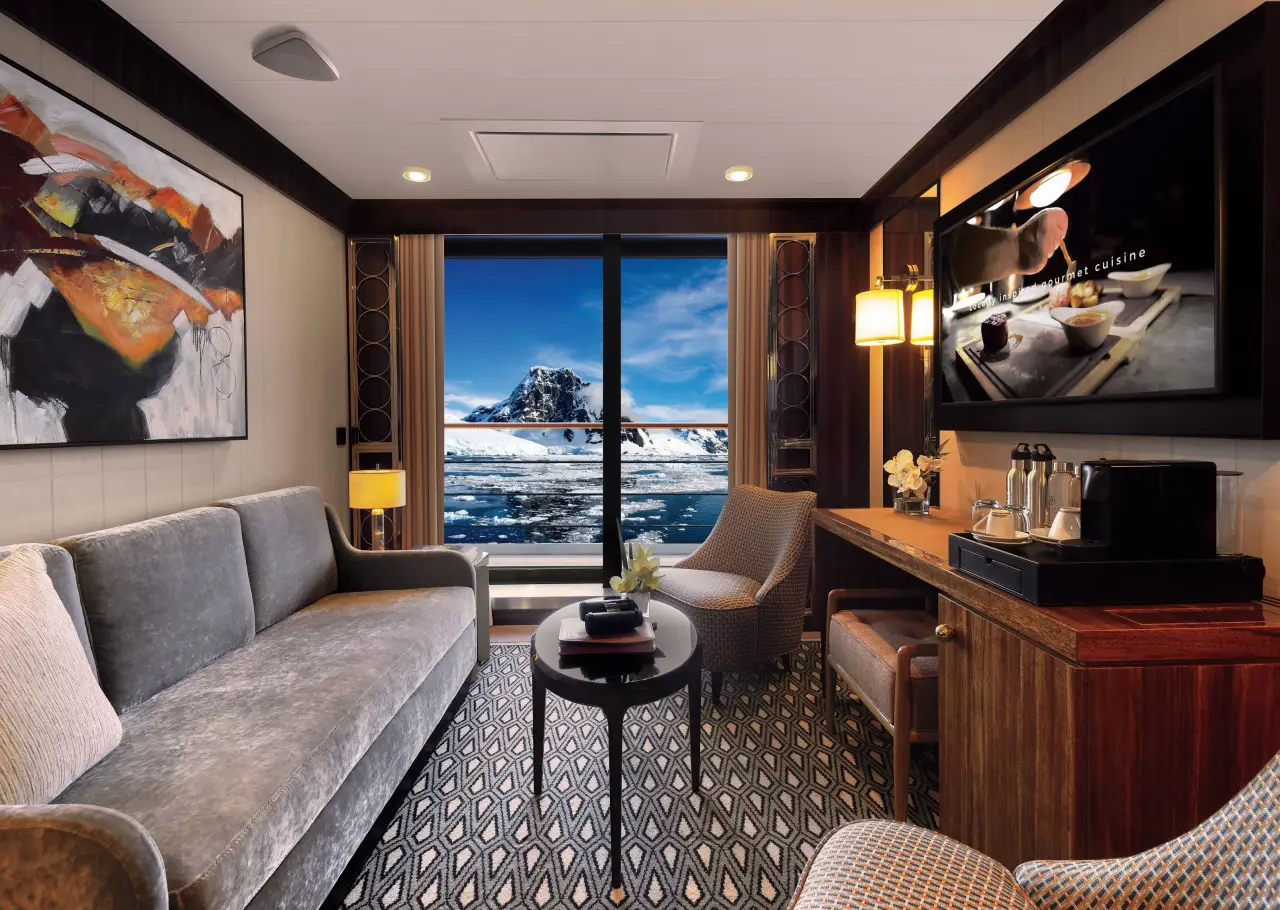 Atlas Ocean Voyages Introduces All-Suite Accommodation Across Its Fleet 4 Atlas Ocean Voyages reserve suite living room with Antarctic view and luxury cruise interior design