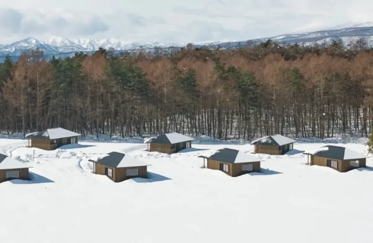 Snow-covered luxury cabins and sauna pavilions at Azuma Farm Koiwai surrounded by forest and mountains in Japan’s Iwate Prefecture