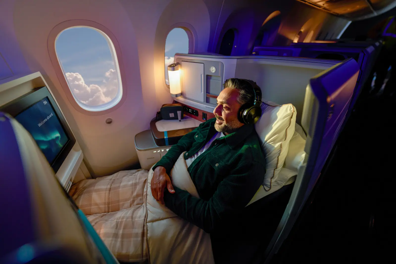 Coming Soon: Alaska Airlines’ Largest Lounge Investment 3 Passenger relaxing in Alaska Airlines international business class suite with lie-flat seat and in-flight entertainment aboard a Boeing 787 Dreamliner.