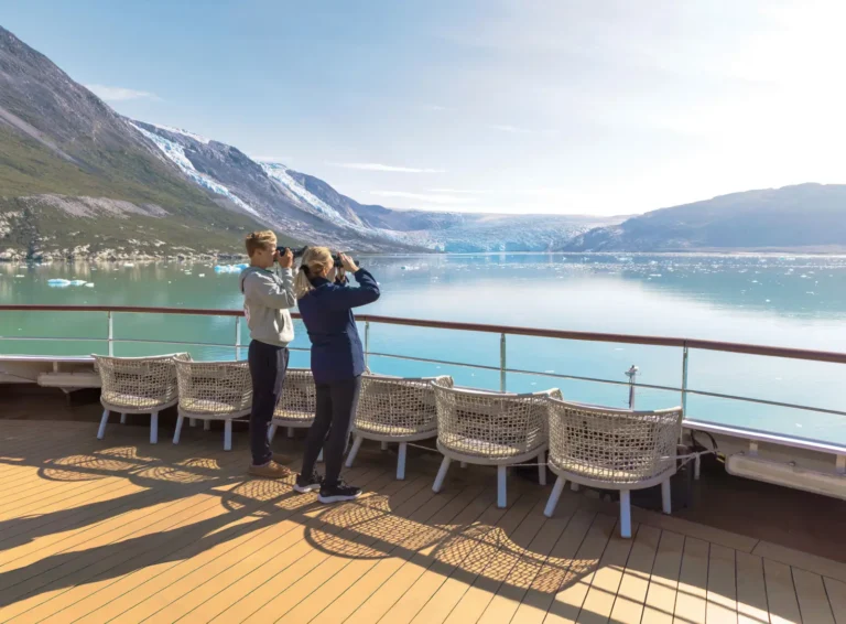 Guests watch glaciers and Arctic landscapes from the deck of an Atlas Ocean Voyages expedition ship in Greenland.