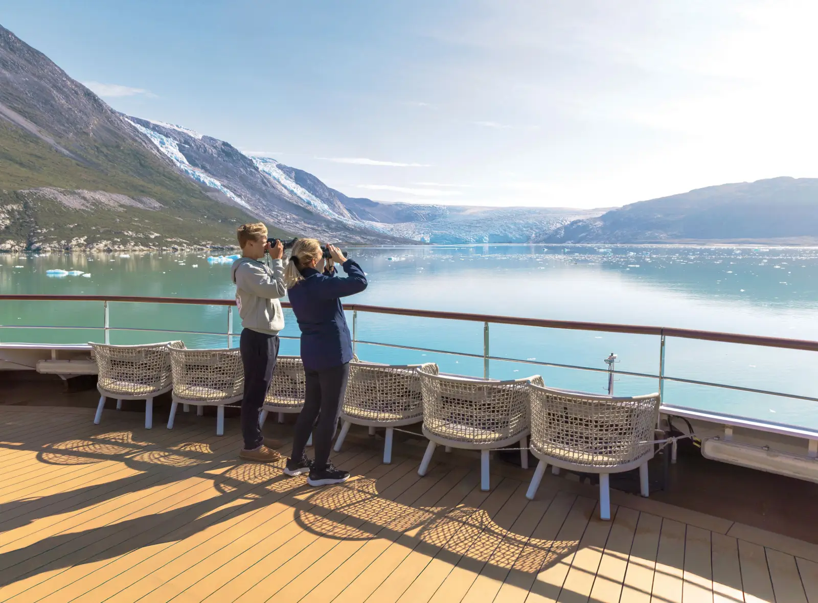 Guests watch glaciers and Arctic landscapes from the deck of an Atlas Ocean Voyages expedition ship in Greenland.