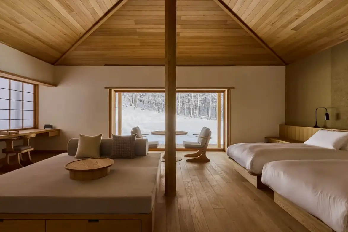 New Boutique Nature Retreat In Japan – Azuma Farm Koiwai - Focuses On Seasonal Farm Life 3 Minimalist guest room at Azuma Farm Koiwai with wooden interiors, twin beds and snowy forest views in Japan