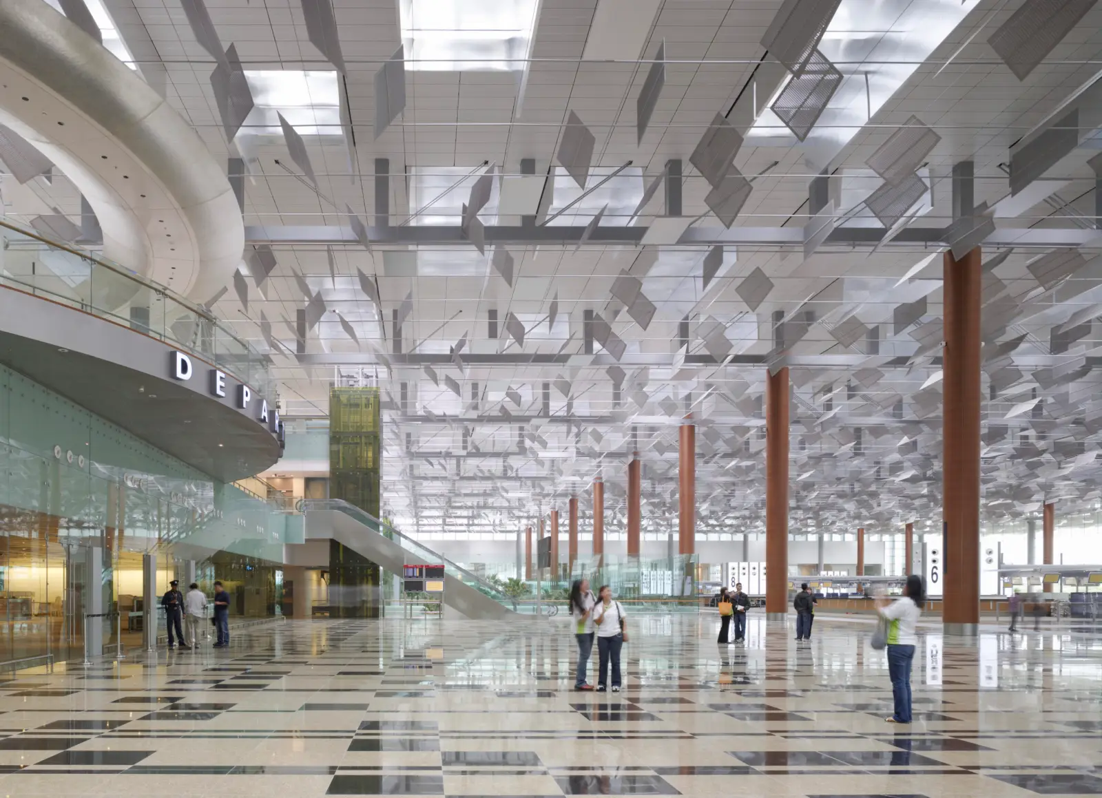 Spacious check-in hall inside Singapore Changi Airport Terminal 3 with high ceilings, columns and travelers walking through the terminal.