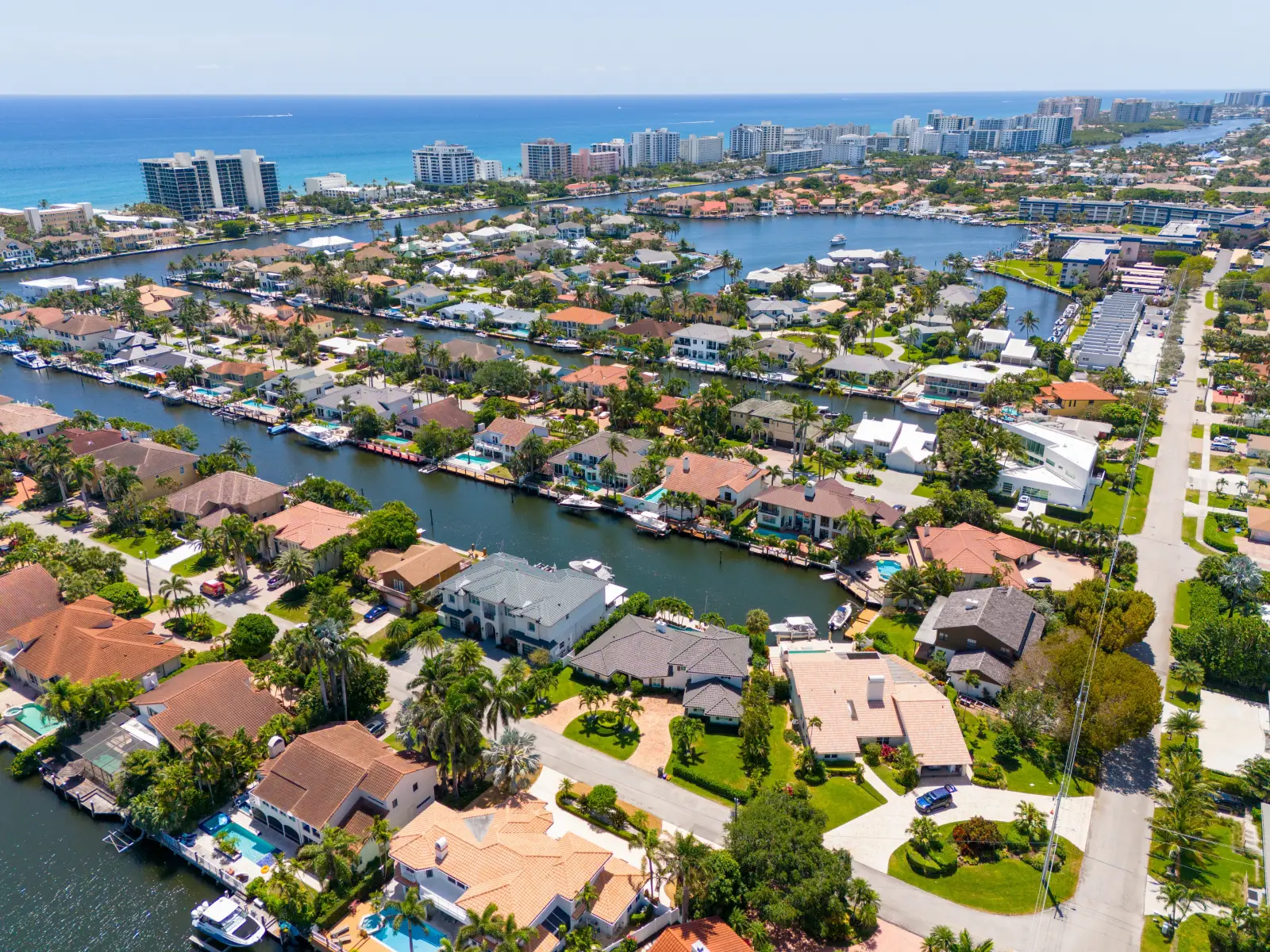 Aerial view of luxury waterfront homes and canals in Delray Beach, Florida, with the Atlantic Ocean in the background.