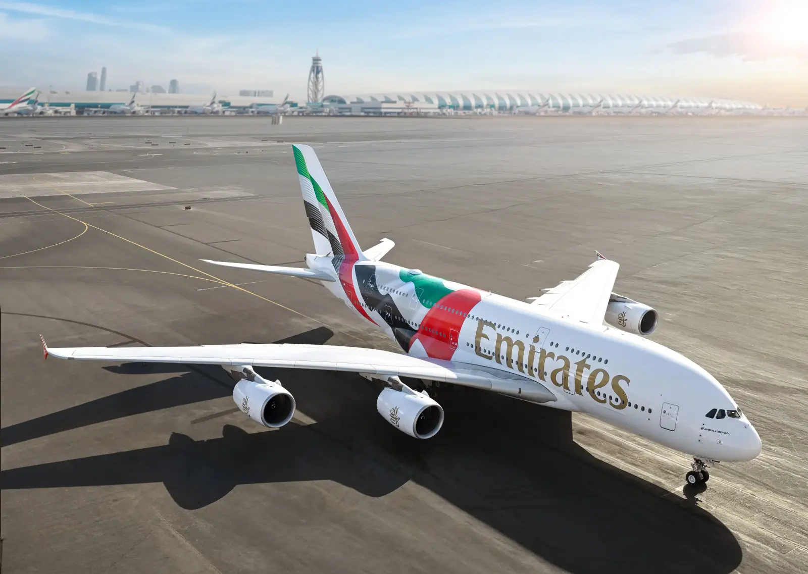 Emirates Airbus A380 aircraft with a special UAE flag livery parked on the apron at Dubai International Airport.