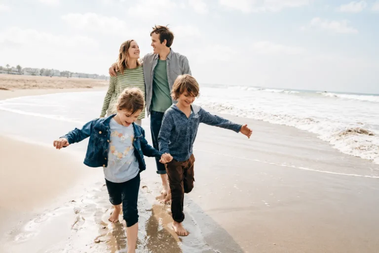 Family with two children walking barefoot along a sandy beach during a relaxed seaside holiday