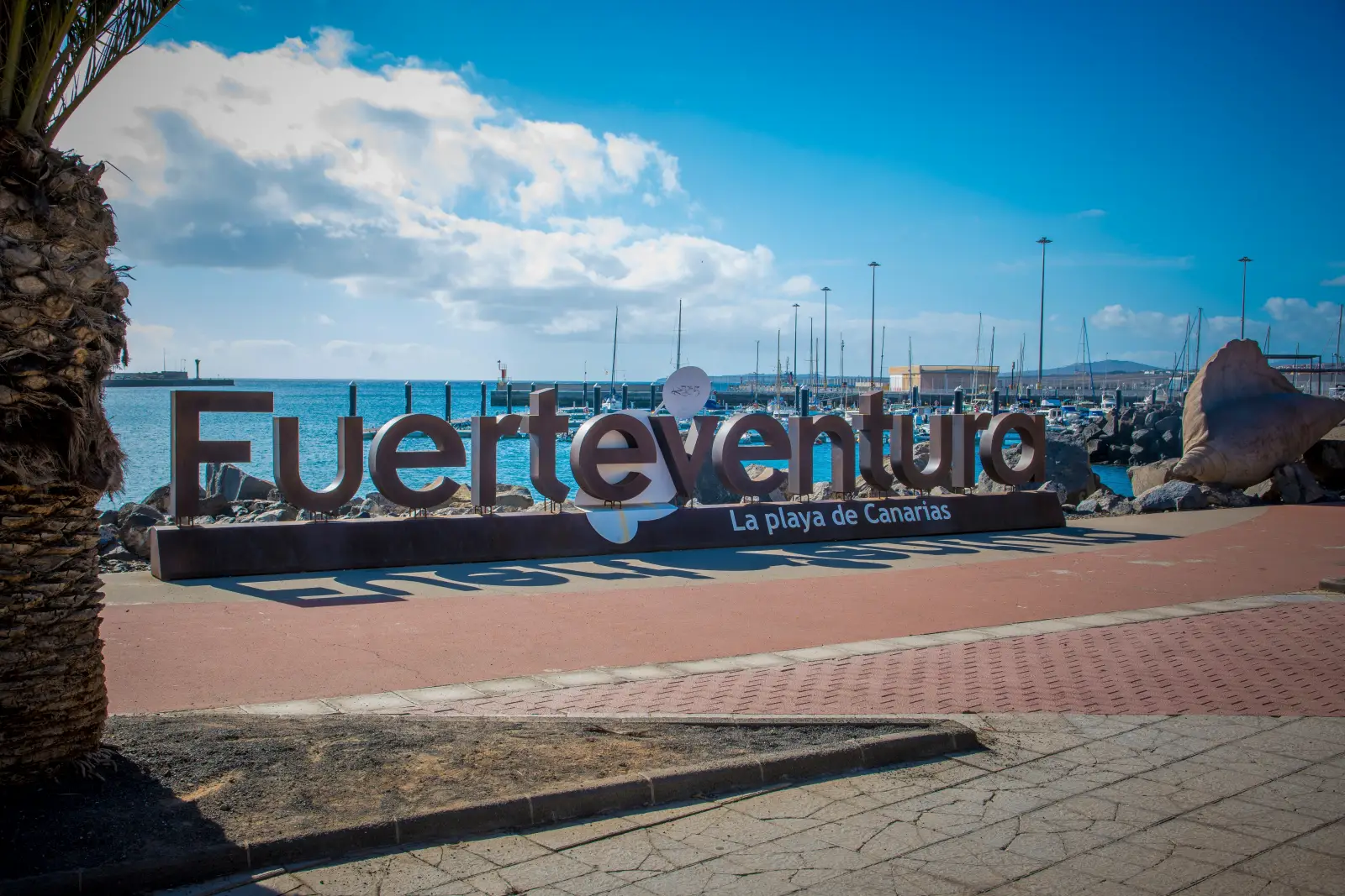 Large Fuerteventura sign beside the marina waterfront in the Canary Islands on a sunny day.