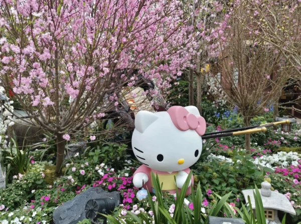 Hello Kitty figure surrounded by pink sakura blossoms and spring flowers at Gardens by the Bay Flower Dome in Singapore.