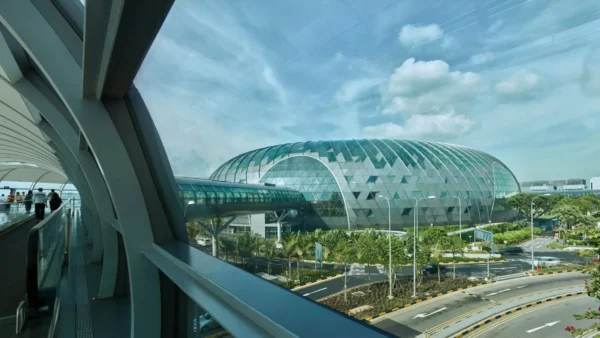 Exterior view of Jewel Changi Airport in Singapore featuring its iconic glass dome architecture connected to the airport Skytrain walkway